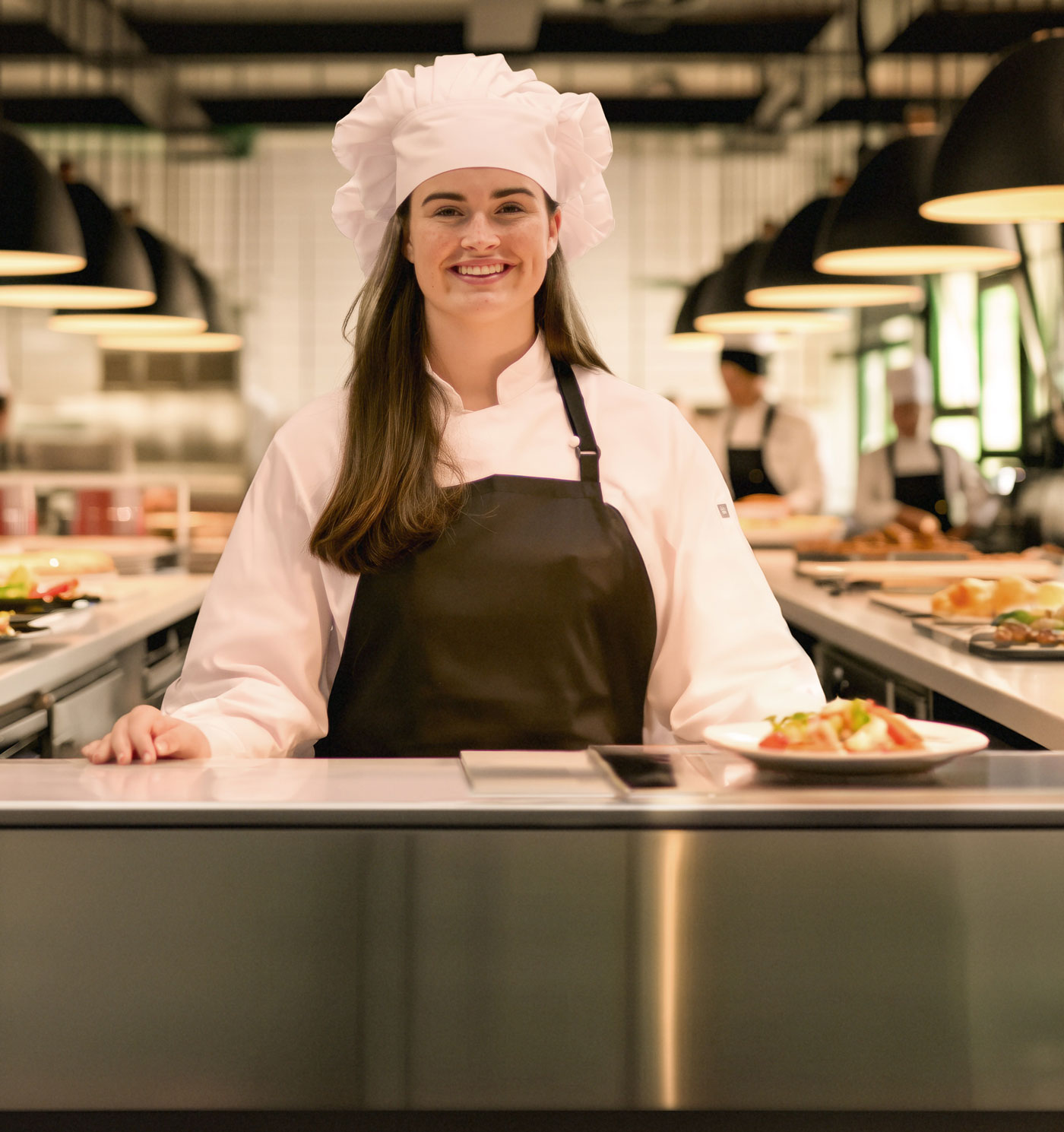 Photo of a St Cuthbert’s girl as a chef, in a busy restaurant kitchen